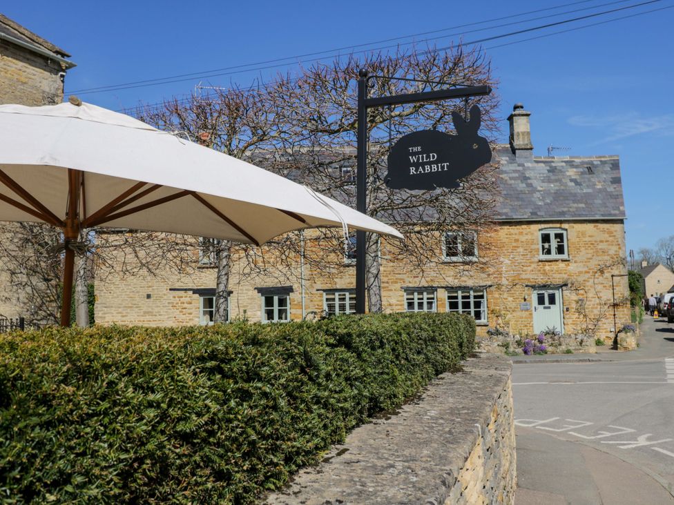 A sign and building with umbrellas and hedge at The Wild Rabbit in Kingham