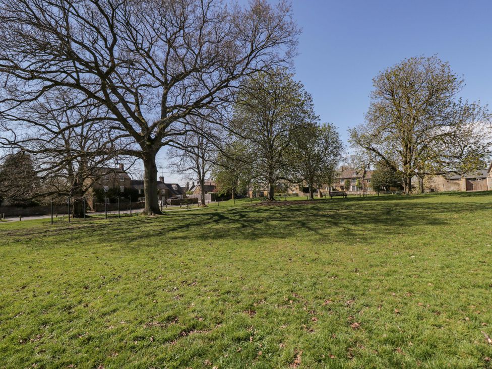 A grassy area with trees and buildings at The Tap Room in Kingham
