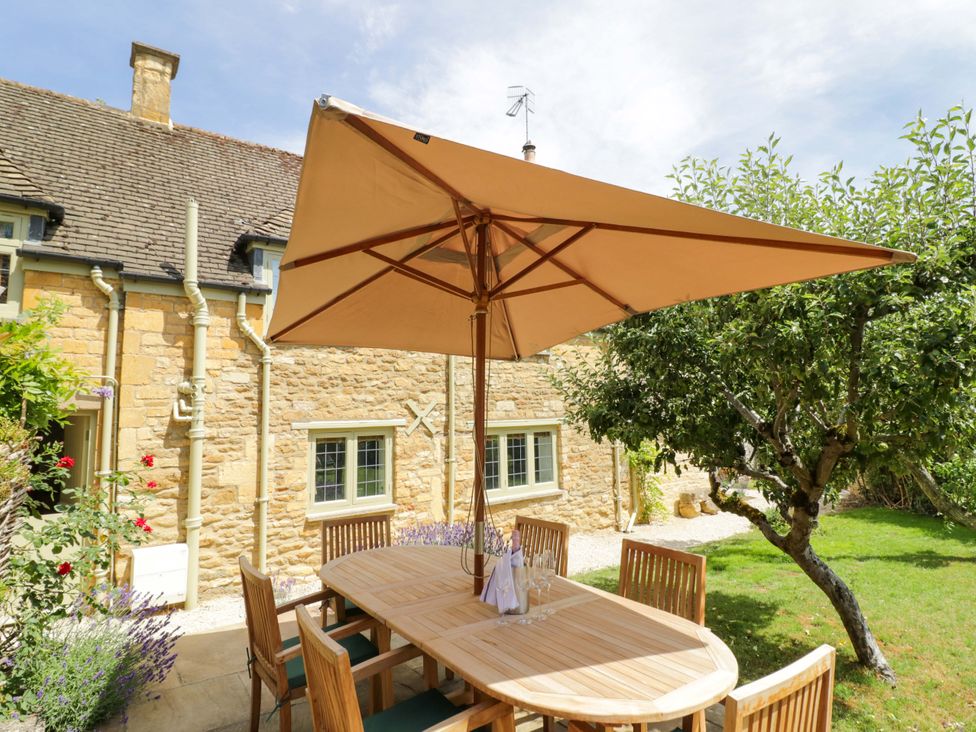 A garden with a wooden table and umbrella at Wyncliffe in Chipping Campden