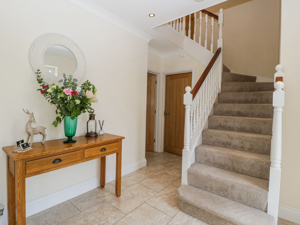 A hallway with a staircase and a table featuring flowers and decorative items at Bell Garden in Stow-On-The-Wold