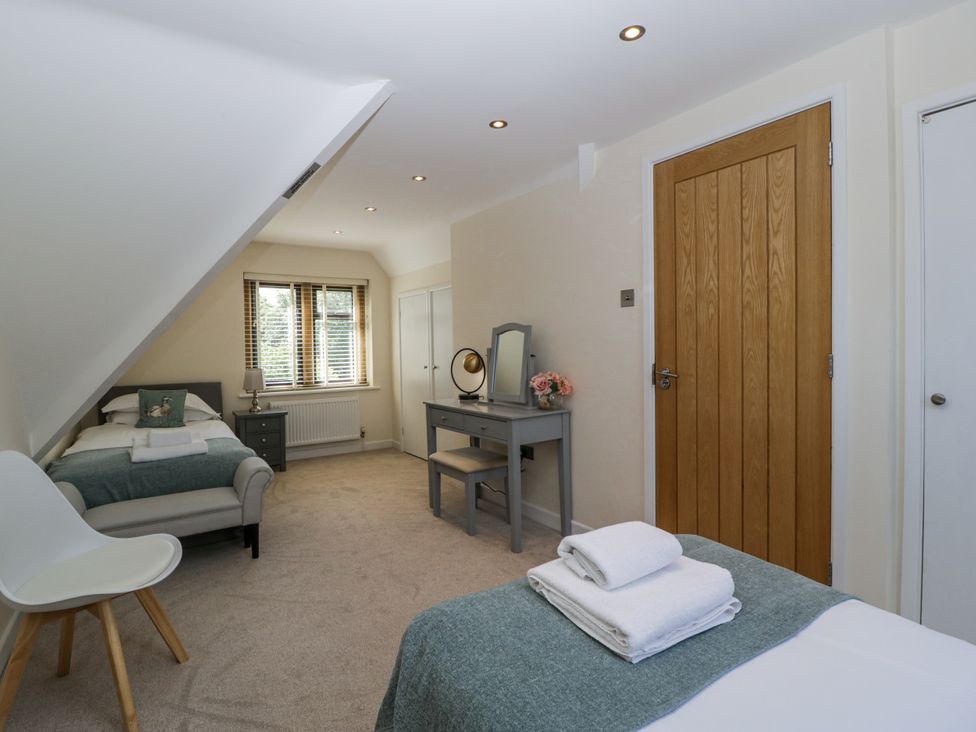 A bedroom with two beds, a dresser, and a mirror at Bell Garden in Stow-On-The-Wold