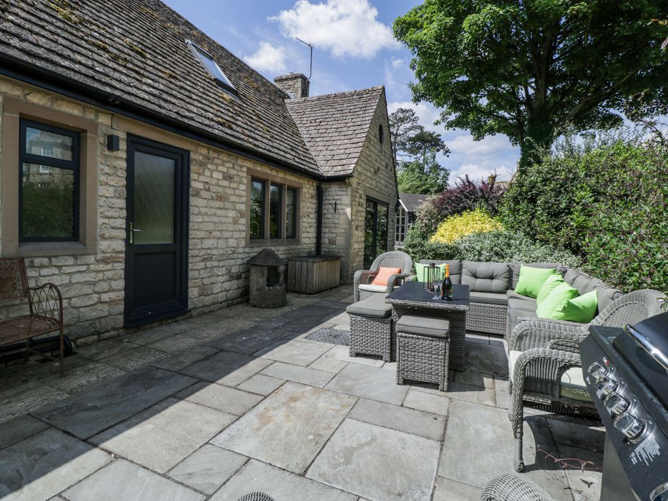An outdoor seating area with a stone house and furniture at Bell Garden Stow-On-The-Wold