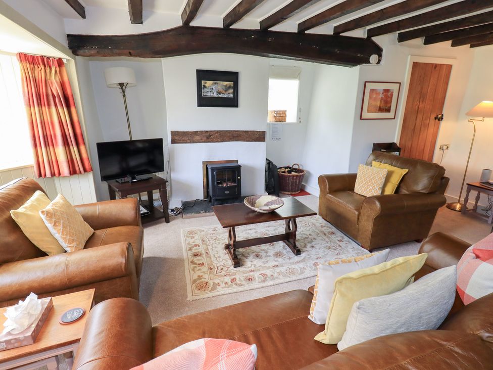 A living room with a sofa, coffee table, and television at Burnside Cottage in Braithwaite