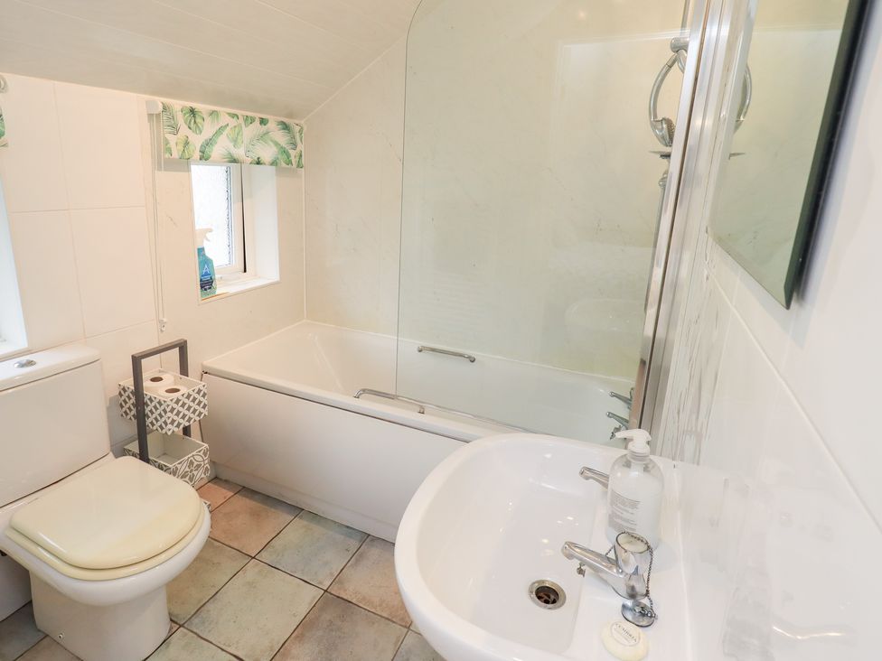 A bathroom with a toilet, bathtub, sink, and storage at Hazelmere in Keswick
