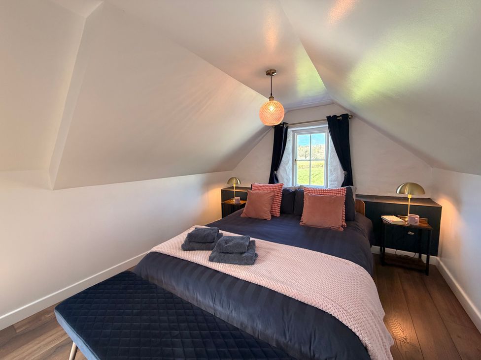 A bedroom with a bed and nightstands at Pensarngerrig in Rhydlewis