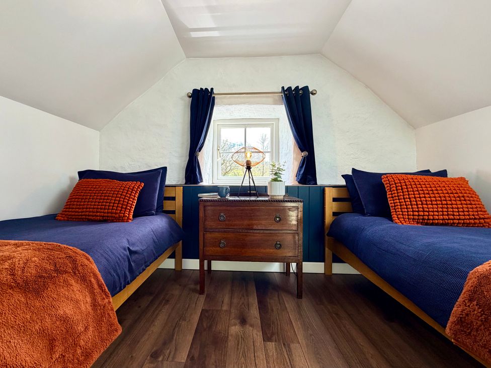 A bedroom with two beds and a nightstand at Pensarngerrig in Rhydlewis
