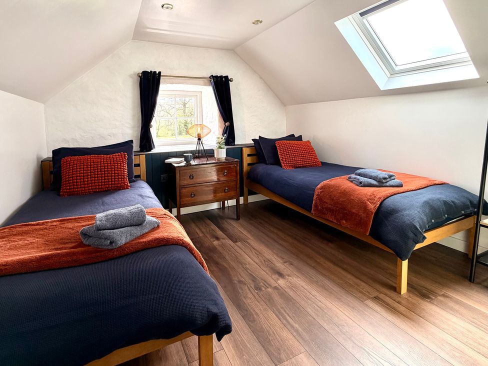 A bedroom with two beds and a window at Pensarngerrig in Rhydlewis