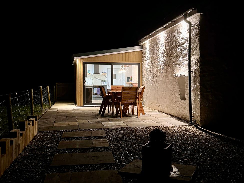 An outdoor patio with a dining table and chairs at Pensarngerrig Rhydlewis