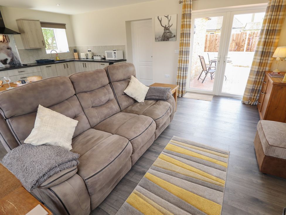 A living room with a sofa and kitchen area at The Old Stables in Folkingham