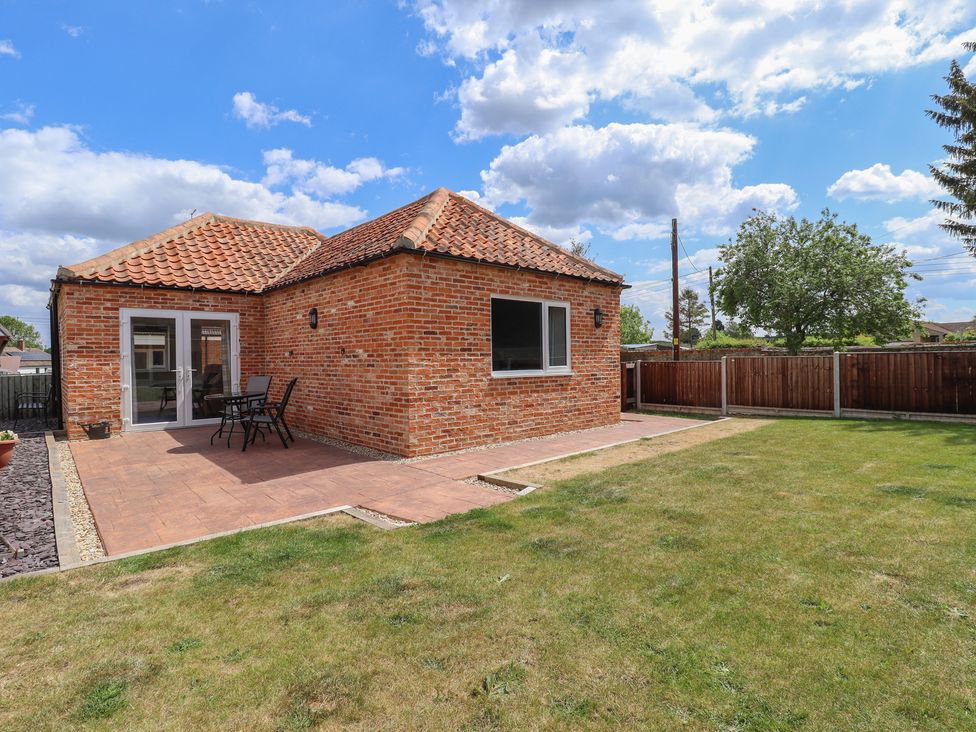 A garden with a brick house and patio area at The Old Stables in Folkingham
