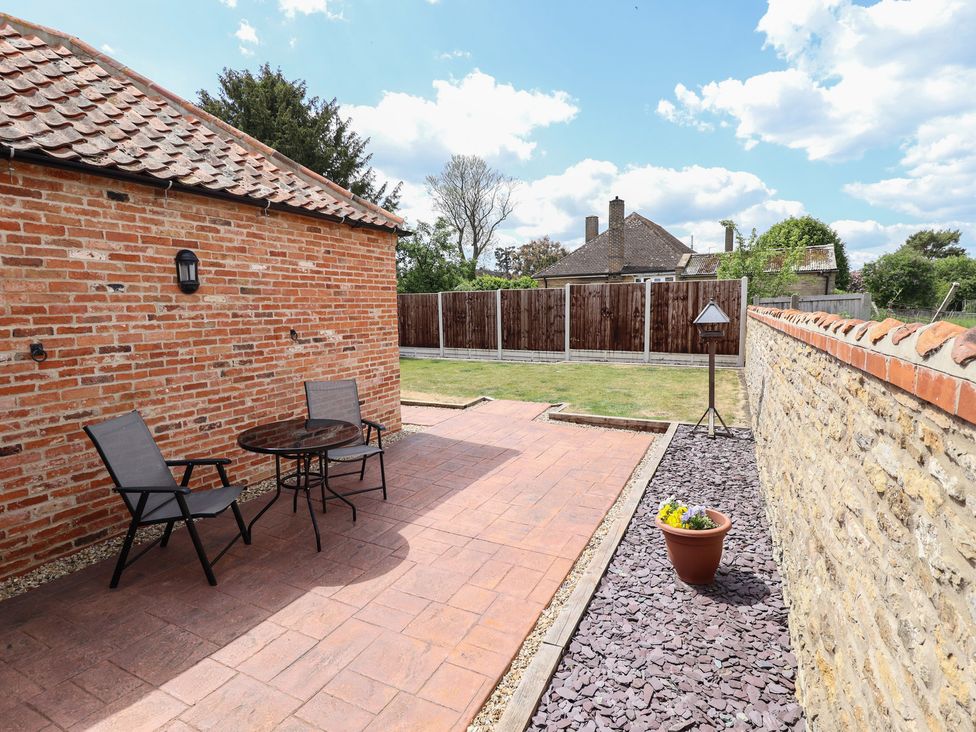 A garden with a patio set and flower pot at The Old Stables in Folkingham
