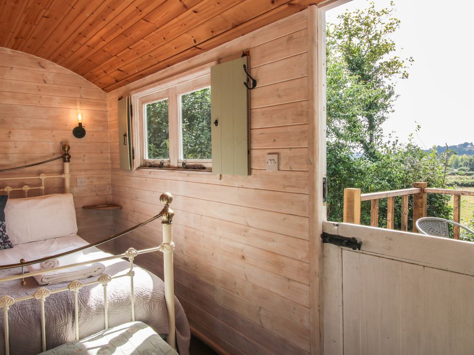 A bedroom with a bed and a window at Aston - Shepherd Hut Aston On Clun