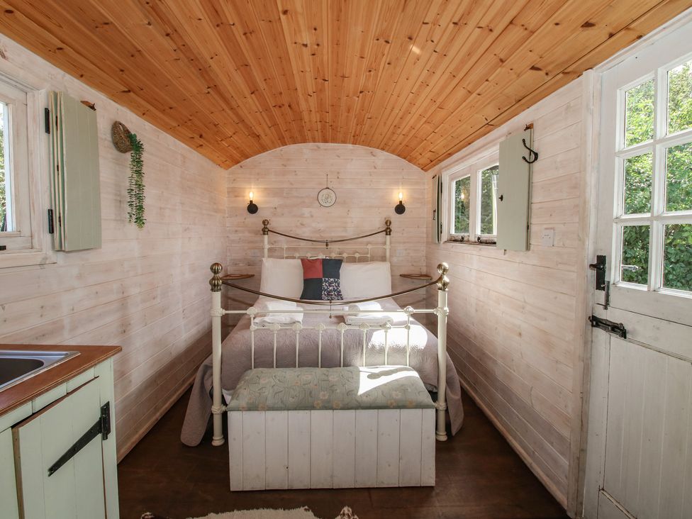 A bedroom with a bed and wooden furnishings at Aston - Shepherd Hut in Aston On Clun