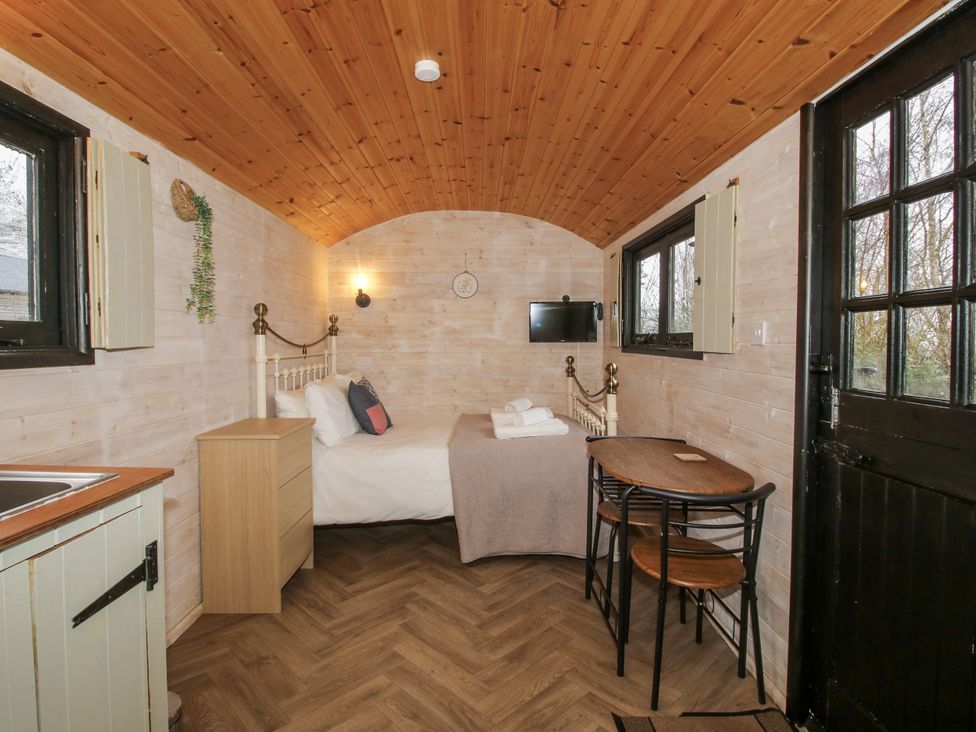 A sleeping area with a bed, table and chairs at Aston - Shepherd Hut in Aston On Clun