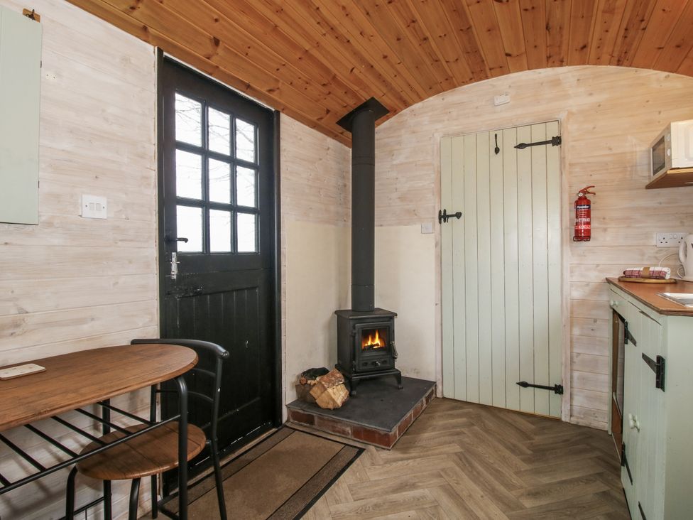 A kitchen with a fireplace and table at Aston - Shepherd Hut Aston On Clun