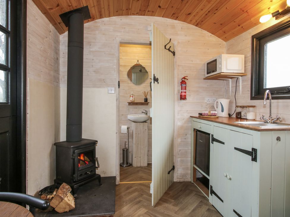 A kitchen with a stove and sink at Aston - Shepherd Hut Aston On Clun