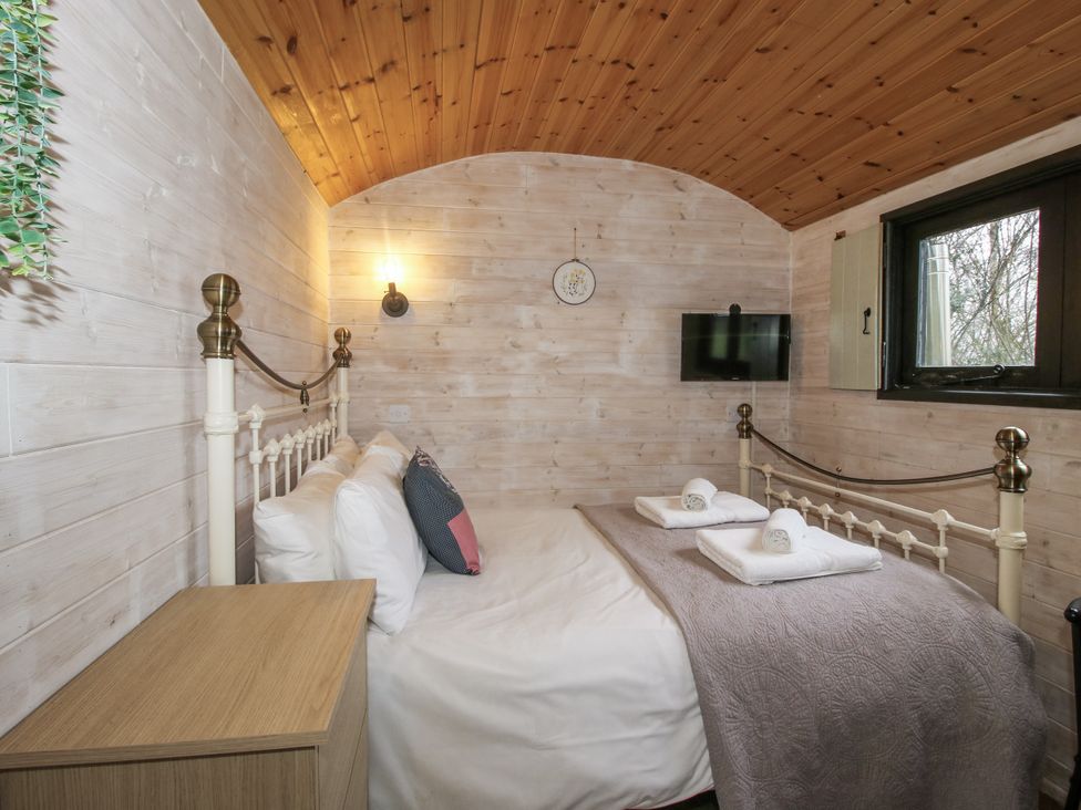 A bedroom with a bed and television at Aston - Shepherd Hut Aston On Clun