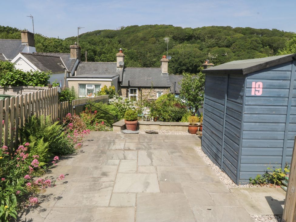 A garden with a stone patio and a shed at Maenllwyd Borth-Y-Gest near Porthmadog