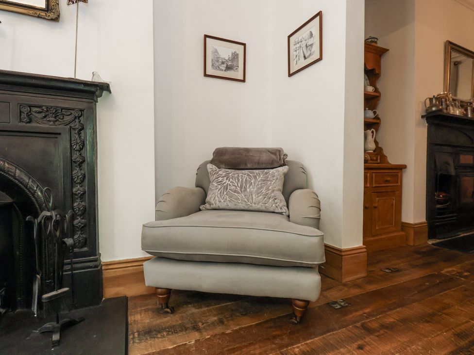 A living room with an armchair and a fireplace at Charlotte House in Whitby