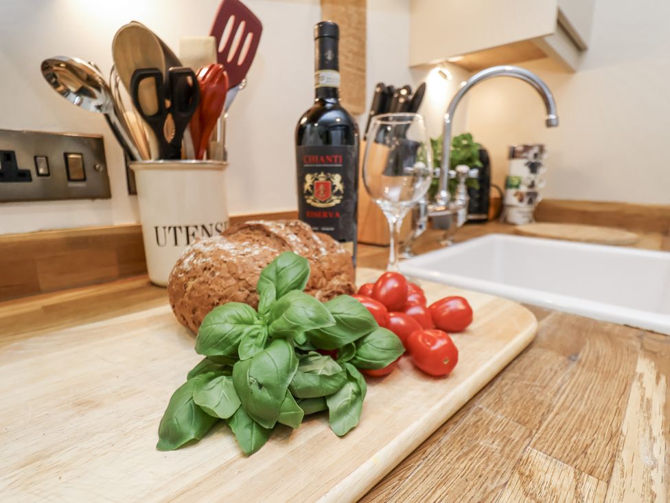 A kitchen countertop with basil, cherry tomatoes, bread, wine bottle, and glass at Charlotte House Whitby