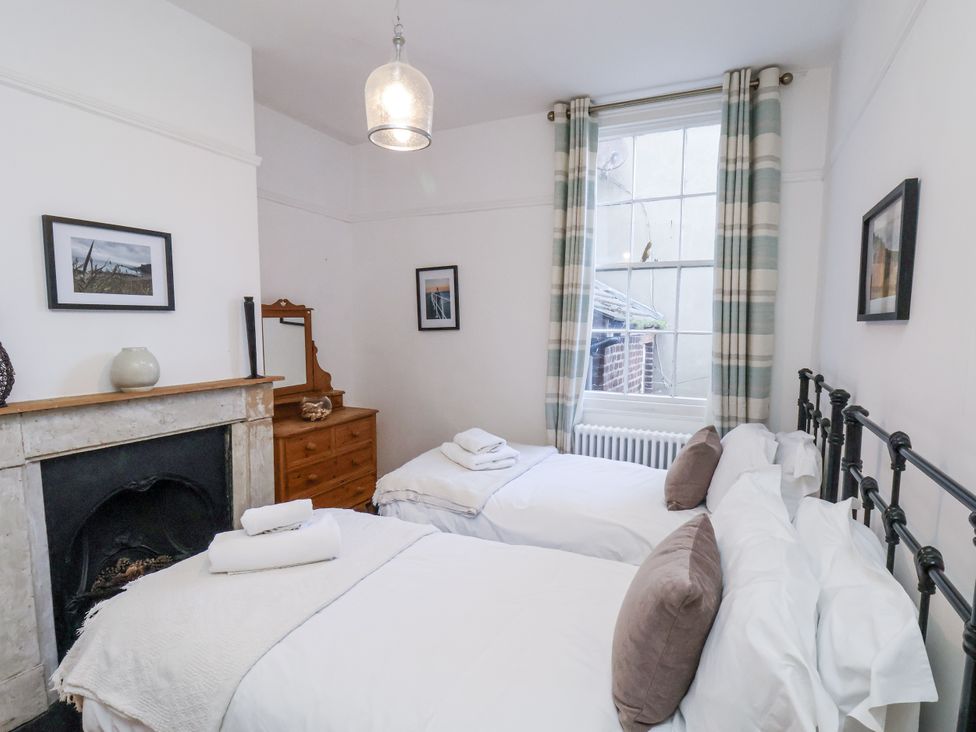 A bedroom with two beds and a mirror at Charlotte House in Whitby