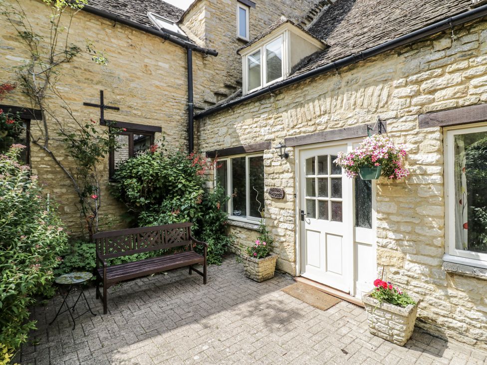 An outdoor area with a bench and flower pots at Dairy Cottage in Witney