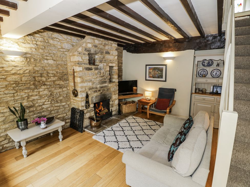 A living room with a fireplace and television at Dairy Cottage in Witney