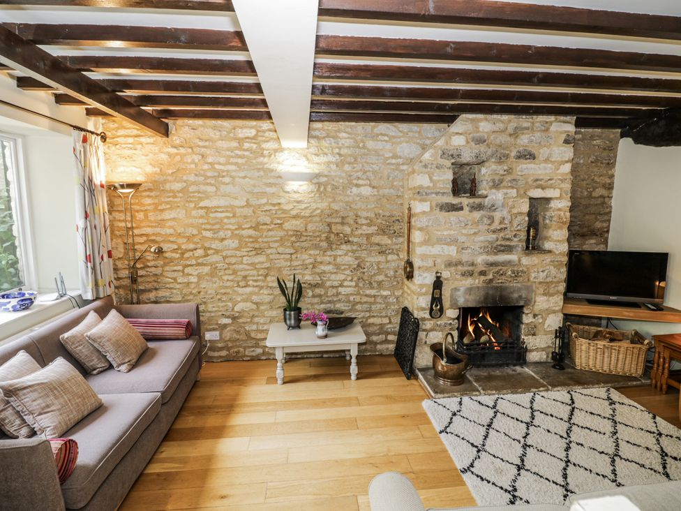 A living room with a sofa and a fireplace at Dairy Cottage in Witney
