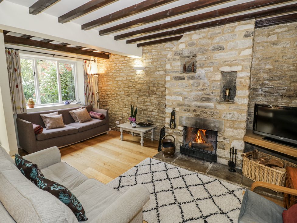 A living room with a fireplace and sofa at Dairy Cottage in Witney
