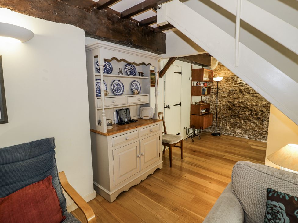 A living room with a table and shelves at Dairy Cottage in Witney