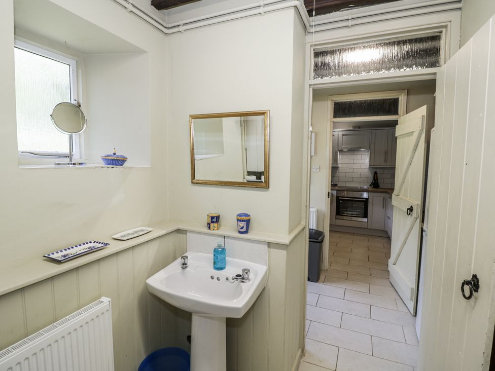 A bathroom with a sink and mirror with access to a kitchen at Dairy Cottage in Witney