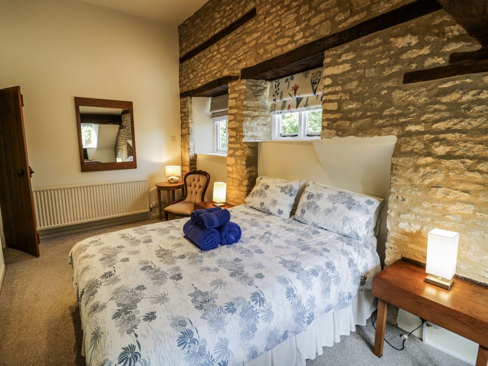 A bedroom with a bed and a mirror at Dairy Cottage in Witney
