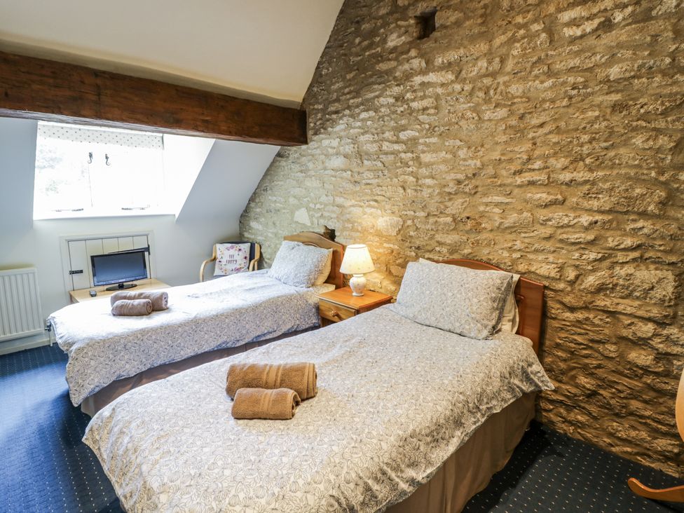 A bedroom with two beds and a television at Dairy Cottage in Witney