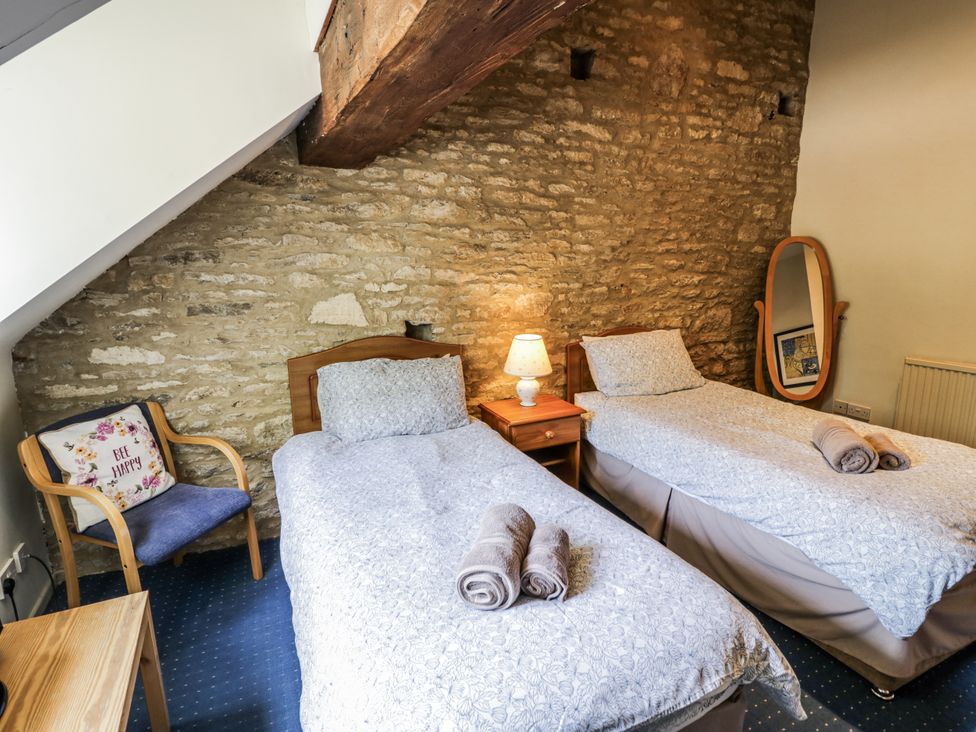 A bedroom with two single beds and a nightstand at Dairy Cottage in Witney