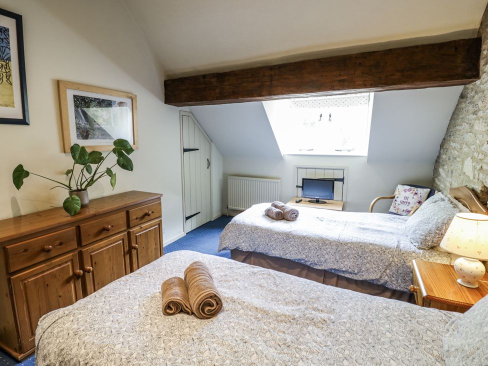 A bedroom with two beds and a cabinet at Dairy Cottage in Witney