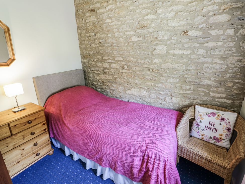 A bedroom with a bed and bedside lamp at Dairy Cottage in Witney