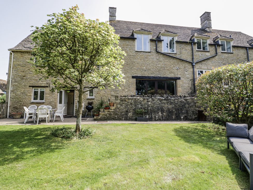 A garden with a house, chairs and a barbecue at Dairy Cottage in Witney