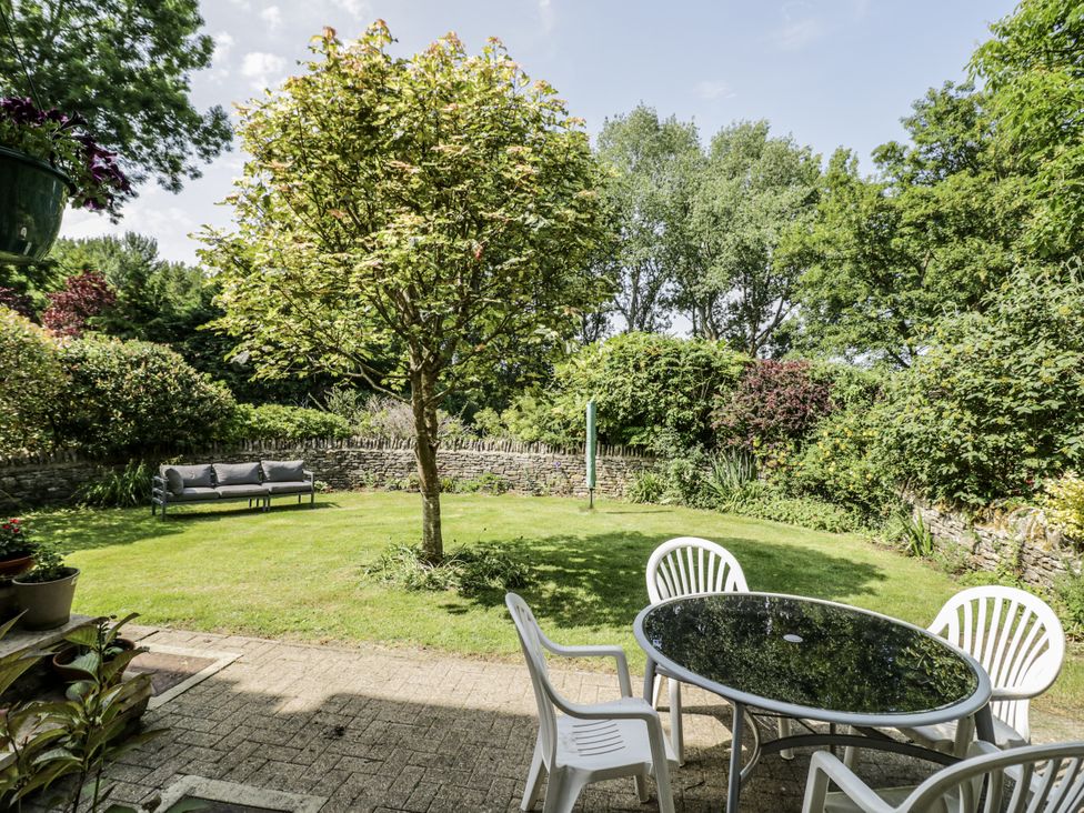 A garden with a tree, seating area and table at Dairy Cottage in Witney