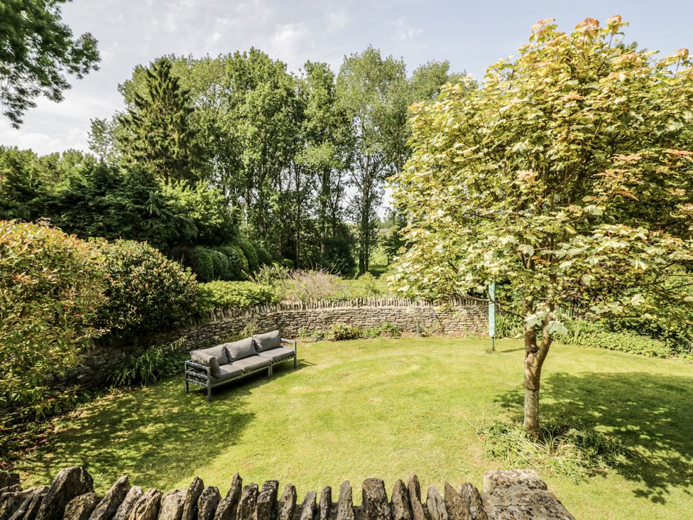 A garden with a sofa and trees at Dairy Cottage in Witney