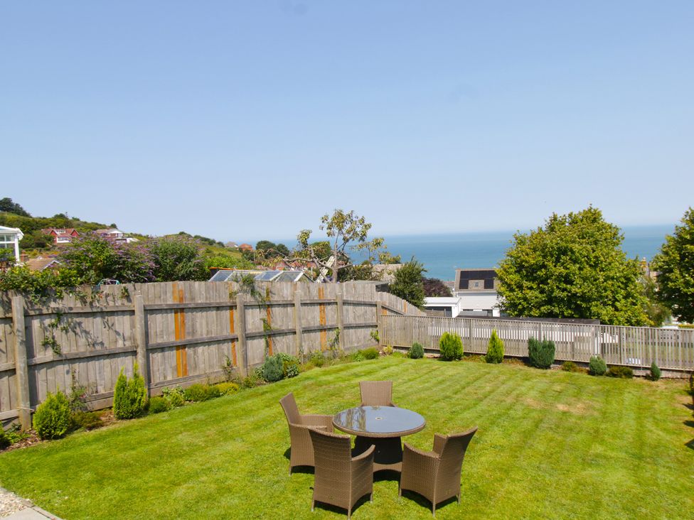 A garden with a table and chairs overlooking the ocean at 65 Channel View Ilfracombe