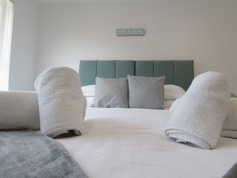 A bedroom with bed and towels rolled on it at 65 Channel View in Ilfracombe