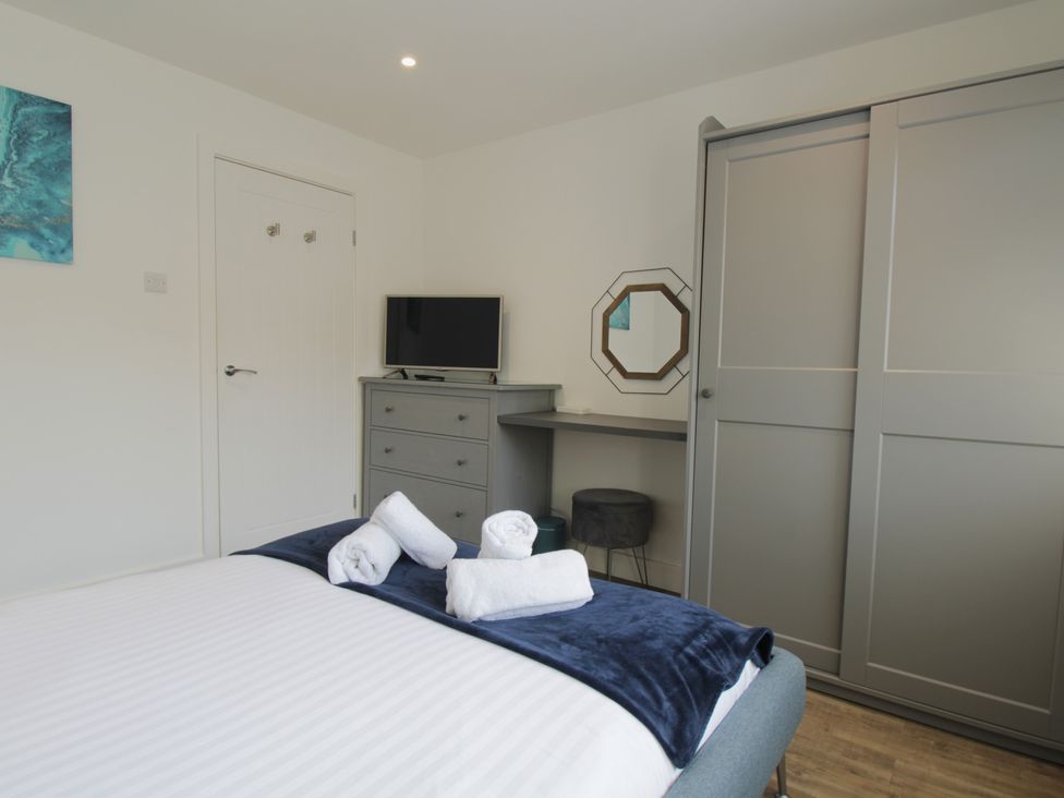 A bedroom with a bed, dresser, television, and mirror at 65 Channel View in Ilfracombe
