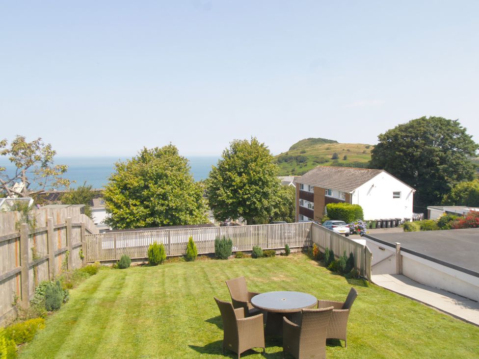 A garden with a table and chairs overlooking the ocean at 65 Channel View Ilfracombe