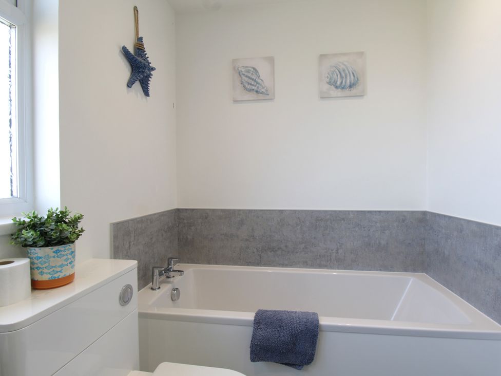A bathroom with a bathtub and toilet at 65 Channel View in Ilfracombe