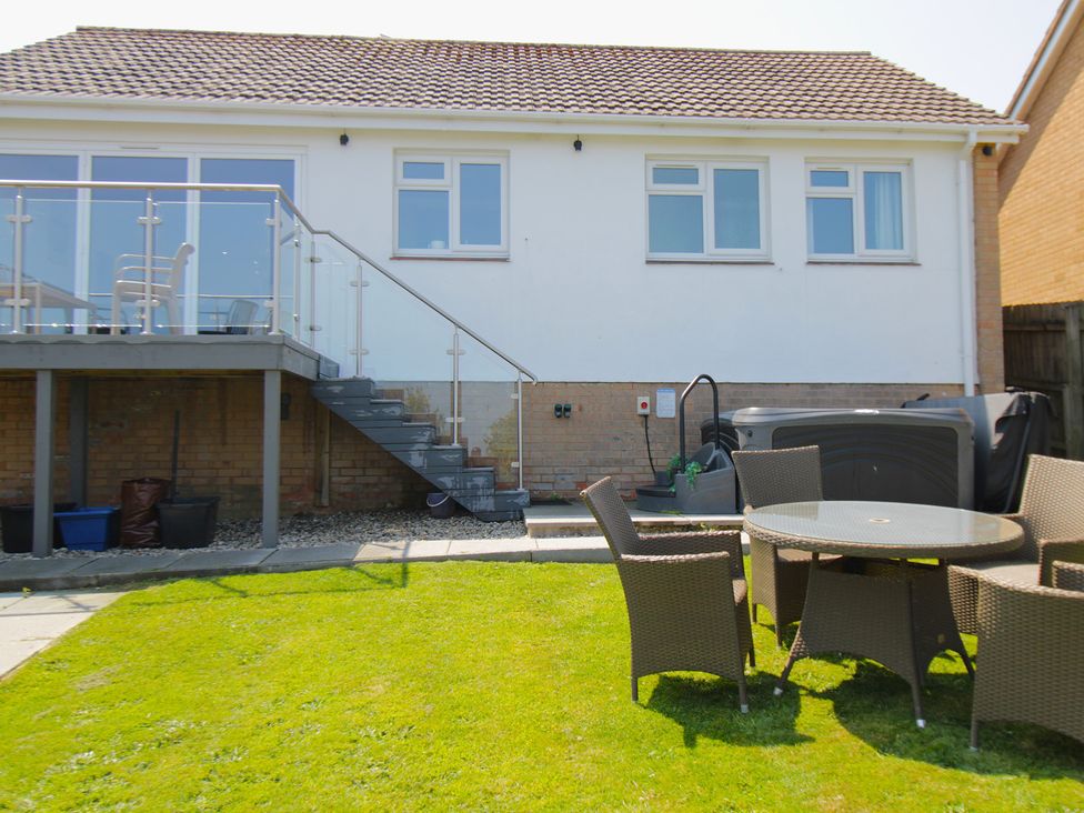 A garden with a table and chairs near a hot tub at 65 Channel View in Ilfracombe