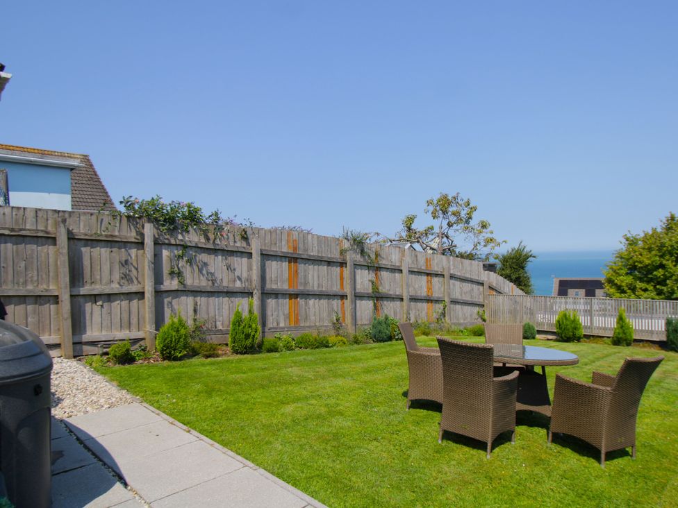 A garden with a table and chairs overlooking the sea at 65 Channel View Ilfracombe