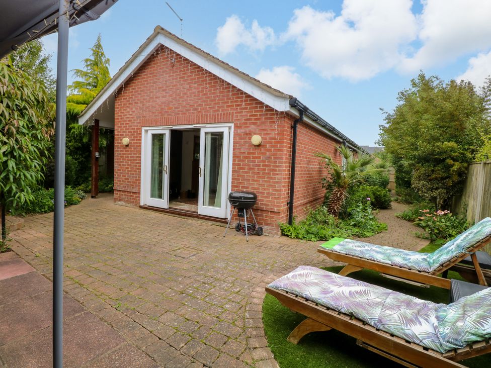 A garden with sun loungers and a grill at Birch Cottage in Brundall
