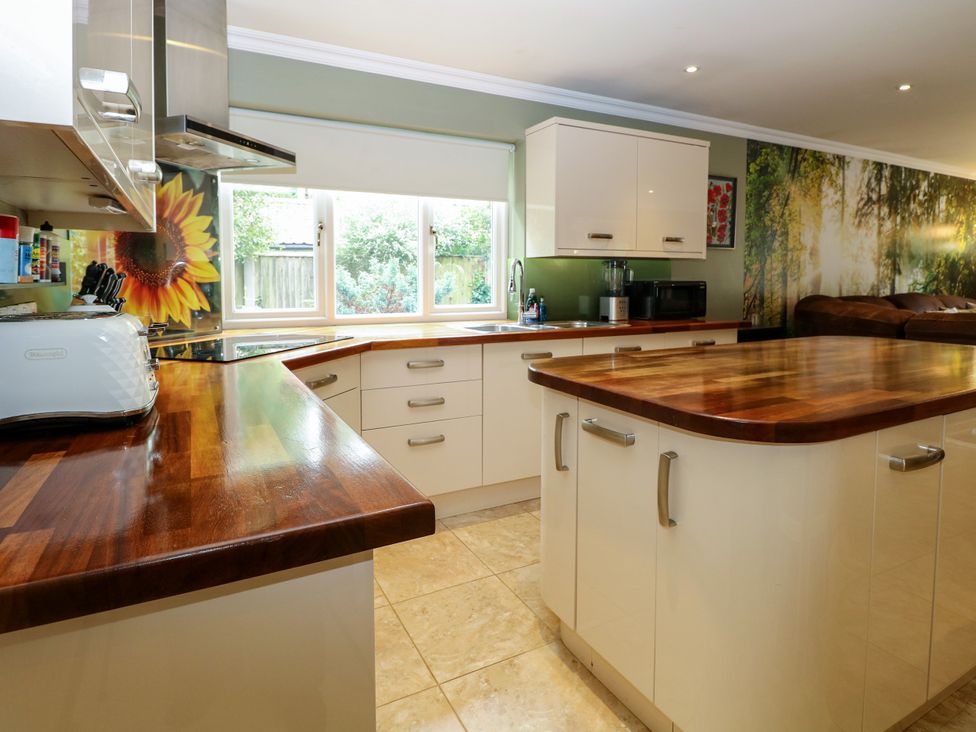 A kitchen with a kitchen island and cabinets at Birch Cottage in Brundall