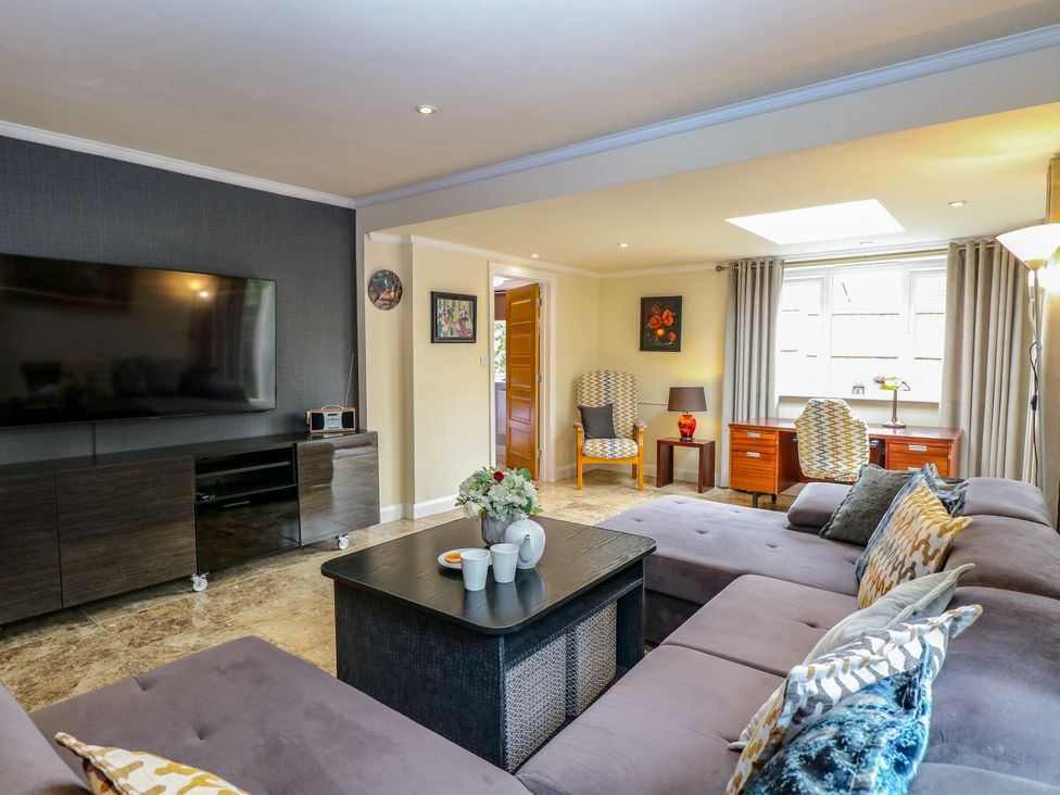 A living room with a sofa and television at Birch Cottage in Brundall