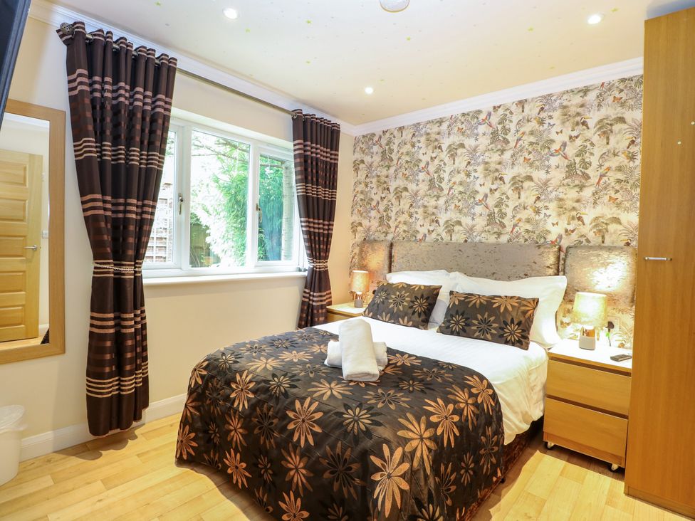 A bedroom with a bed and window at Birch Cottage in Brundall